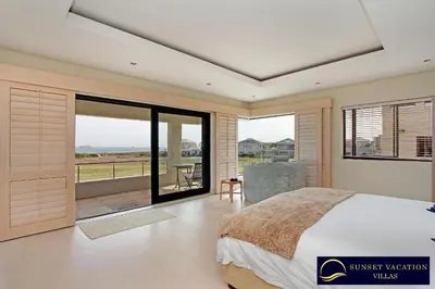 a bedroom with a bed and a view of the ocean at Kite Surfers Beach Villa in Cape Town