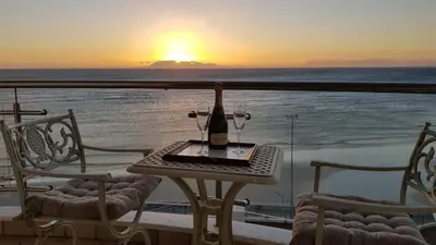a table with a bottle of wine sitting on a balcony with the sunset at Hibernian Towers 807, Beach Road, Strand in Strand