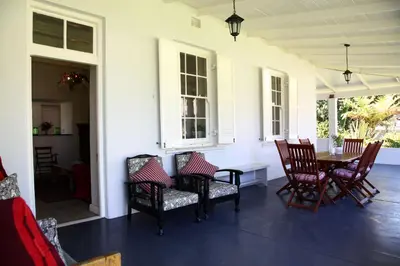 a porch with chairs and a table and a table and chairs at Verandah House in Hermanus