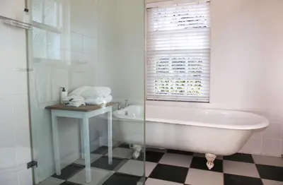 a white bathroom with a tub and a window at Verandah House in Hermanus