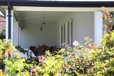 a porch of a house with flowers and plants at Verandah House in Hermanus