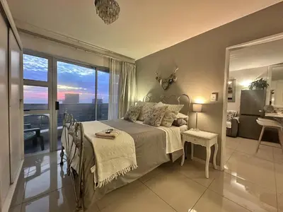a bedroom with a bed and a large window at Seaview Kite Beach Holiday Apartment in Cape Town