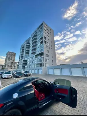 a black car parked in front of a tall building at Seaview Kite Beach Holiday Apartment in Cape Town
