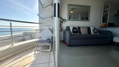 a living room with a couch and a view of the ocean at Seaview Kite Beach Holiday Apartment in Cape Town