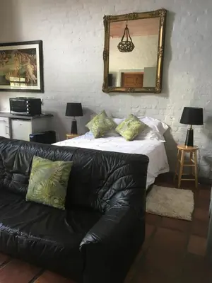 a black leather couch in a living room with a mirror at Protea Studio Franschhoek Central in Franschhoek