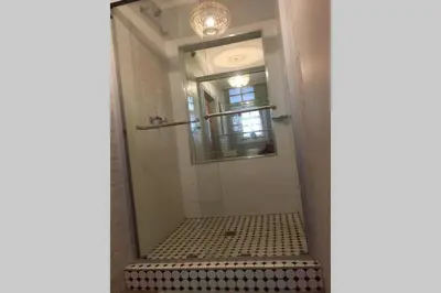 a bathroom with a shower with a black and white tile floor at Protea Studio Franschhoek Central in Franschhoek