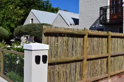 a wooden fence with a trash can in front of it at Protea Studio Franschhoek Central in Franschhoek