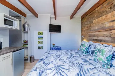a bedroom with a bed and a wooden wall at Protea Room Franschhoek Central in Franschhoek