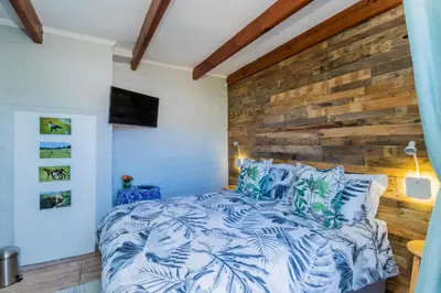 a bedroom with a wooden accent wall and a bed at Protea Room Franschhoek Central in Franschhoek