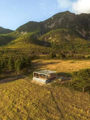 an overhead view of a building in a field with mountains at Hemel 'N Aarde Stud in Hermanus