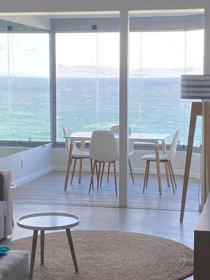 a living room with a table and chairs and the ocean at Bayview 208 in Hermanus