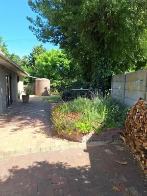 a garden with flowers in a brick driveway at Little Elm Cottage in Cape Town