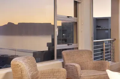 two chairs and a window with a view of the water at Ocean View A603 in Cape Town