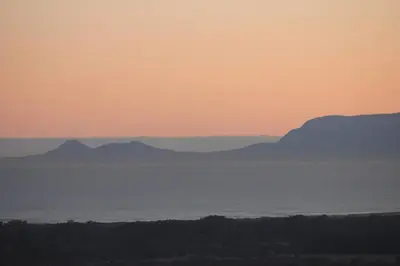 a sunset over the water with mountains in the background at Somerset-West, Heldervue in Cape Town