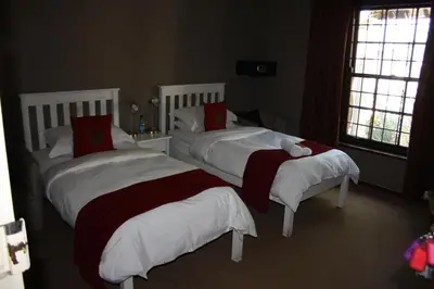 a bedroom with two beds with red and white blankets at The Vinelands on Alpha Guest House in Cape Town