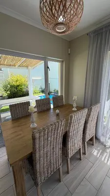 a dining room with a wooden table and chairs at Onrus Holiday Home on Private Estate with Pool in Hermanus
