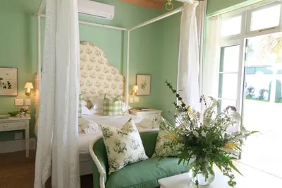 a bedroom with a bed and a couch and a window at La Cotte The Manor House in Franschhoek