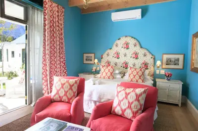 a bedroom with a bed and two chairs at La Cotte The Manor House in Franschhoek