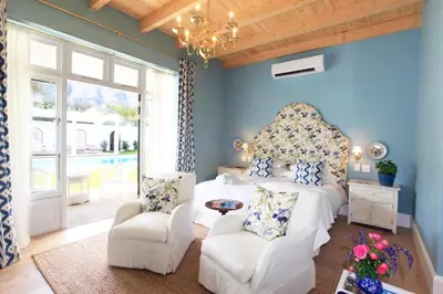 a bedroom with a large bed and two chairs at La Cotte The Manor House in Franschhoek