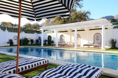 a swimming pool with two lounge chairs and an umbrella at La Cotte The Manor House in Franschhoek