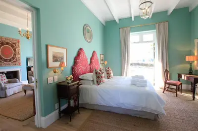 a bedroom with a bed with a red headboard at La Cotte The Manor House in Franschhoek