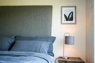 a bed with blue sheets and a lamp on a table at Hilton House in Pringle Bay