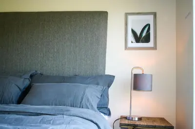 a bed with blue sheets and a lamp on a table at Hilton House in Pringle Bay