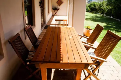 a wooden table and chairs on a patio at Hilton House in Pringle Bay