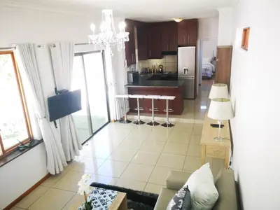 a living room and kitchen with a chandelier at Cottage on Norwood in Cape Town