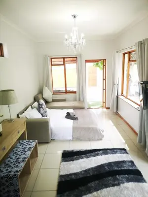 a bedroom with a bed and a chandelier at Cottage on Norwood in Cape Town