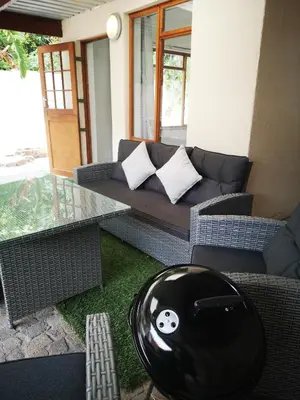 a living room with a couch and a glass table at Cottage on Norwood in Cape Town