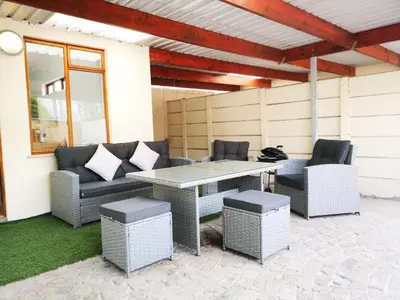 a patio with a table and wicker chairs at Cottage on Norwood in Cape Town