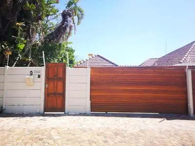 a wooden fence with a white gate and a wooden door at Cottage on Norwood in Cape Town