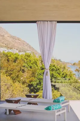 a room with a large window with a bed and a table at Redrock Ocean View Villa in Cape Town
