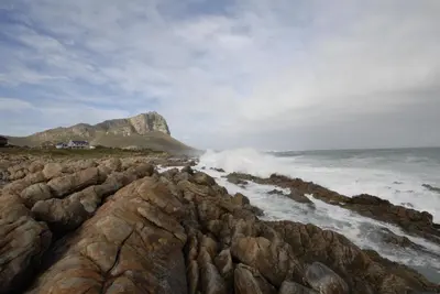 a rocky beach with a mountain in the background at Kleinblom in Pringle in Pringle Bay