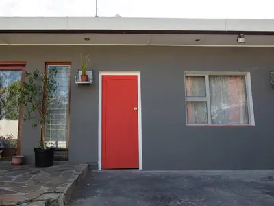 a red door on the side of a house at Lyronne Guest house, Shuttle and Tours in Cape Town