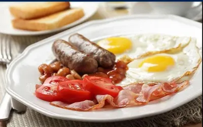 a plate of breakfast food with eggs bacon tomatoes and beans at Casa Milner Guest House in Cape Town