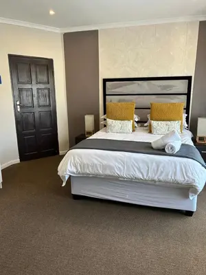 a bedroom with a large white bed with yellow pillows at Casa Milner Guest House in Cape Town