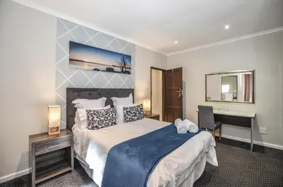 a bedroom with a large bed and a desk at Casa Milner Guest House in Cape Town