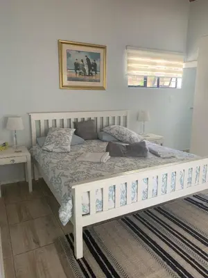 a white bed in a bedroom with two night stands at Hemel-en-See Beach House in Hermanus