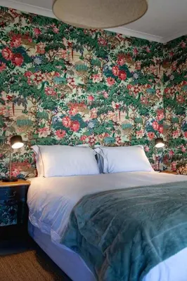 a bedroom with a bed with a floral wallpaper at Villa Le Roc Kleinmond Accommodation in Kleinmond