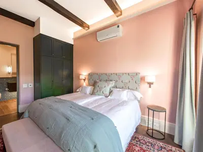 a bedroom with a large white bed with a green headboard at The Vineyard Cottage by L' Amitie Estate in Franschhoek