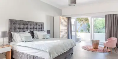a white bedroom with a large bed with a large window at The Views Guesthouse in Somerset West
