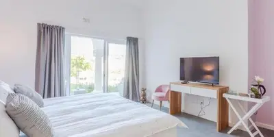 a bedroom with a bed with a television and a desk at The Views Guesthouse in Somerset West