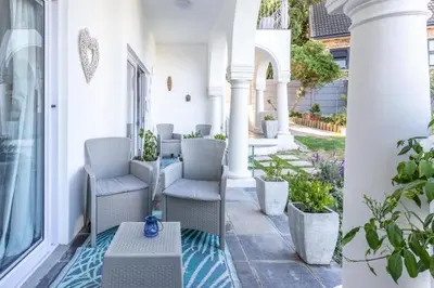 a porch with chairs and a table on a building at The Views Guesthouse in Somerset West