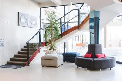 a lobby with two chairs and a staircase with plants at Strand Pavilion in Strand