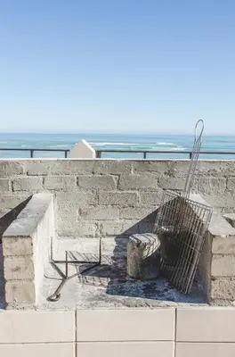 a bench on a wall with the ocean in the background at Strand Pavilion in Strand