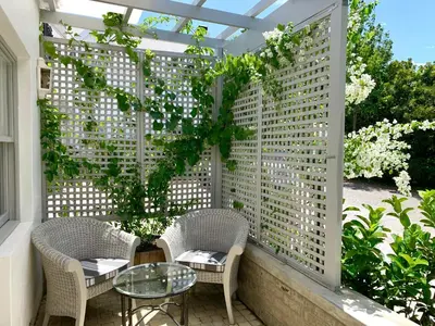 a patio with a pergola and two chairs and a table at One Oak Guest House in Somerset West