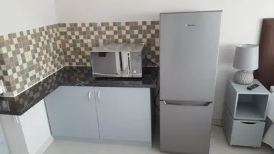 a kitchen with a microwave on a counter next to a refrigerator at Hayley's Place in Cape Town