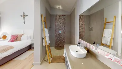 a bedroom with a bed and a bathroom with a sink at McFarlane Residence by Top Destinations Rentals in Hermanus